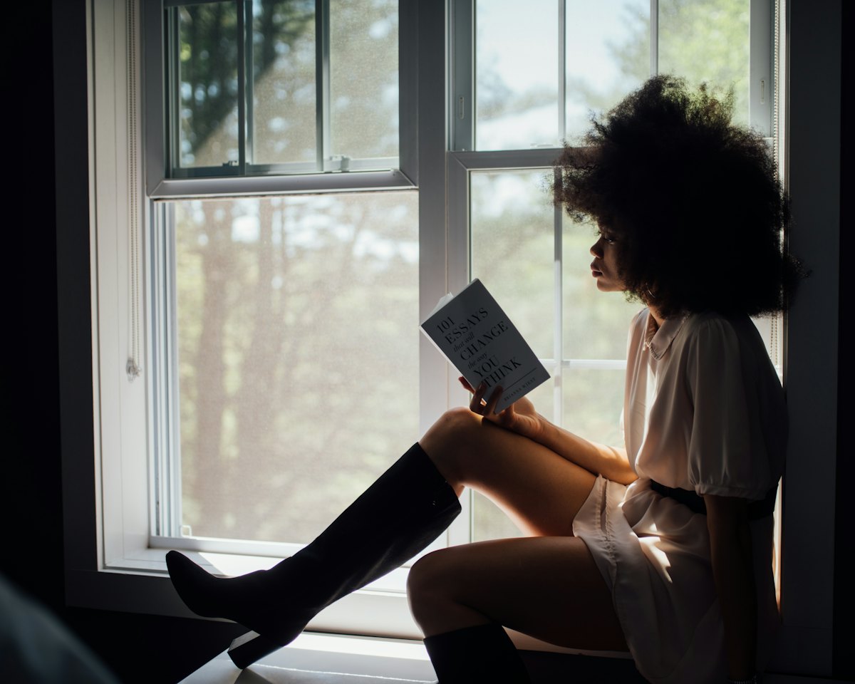 Женщина у окна с книгой: время подумать о себе